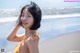 A woman in a yellow bikini standing on a beach.