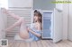 A woman sitting on the floor in front of a refrigerator.
