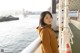 A woman standing on the deck of a boat looking out over the water.