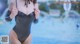 a woman in a black bathing suit standing next to a pool