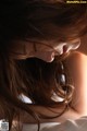 A woman with long brown hair laying on a bed.