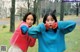 A couple of women standing next to each other in a park.