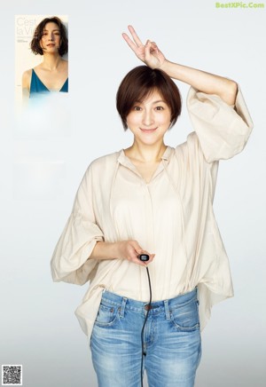 A woman in a white shirt and blue jeans posing for a magazine.