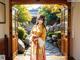 A woman in a kimono standing in front of an open door.