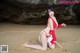 A woman in a red and white bikini sitting on a beach.