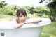 A woman laying in a bathtub with rubber ducks in the background.