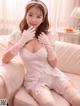 A woman in a white lingerie sitting on a couch.